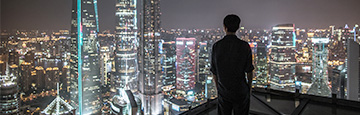 Man looking out over urban cityscape at night